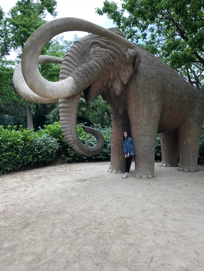 Sculptural Indian elephant nestled in a lush garden, featuring prominent tusks and a welcoming pose.