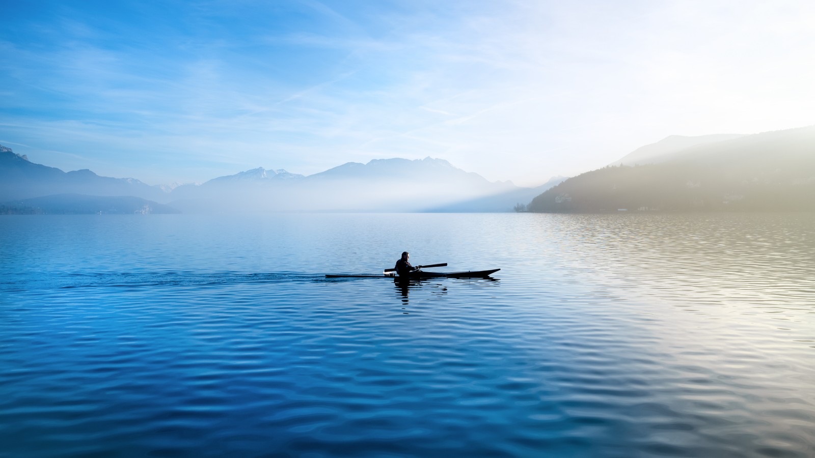 Hombre árabe en un canoa en un lago tranquilo con montañas de fondo (feeds de annecy, kayak, francia, lago, glider)