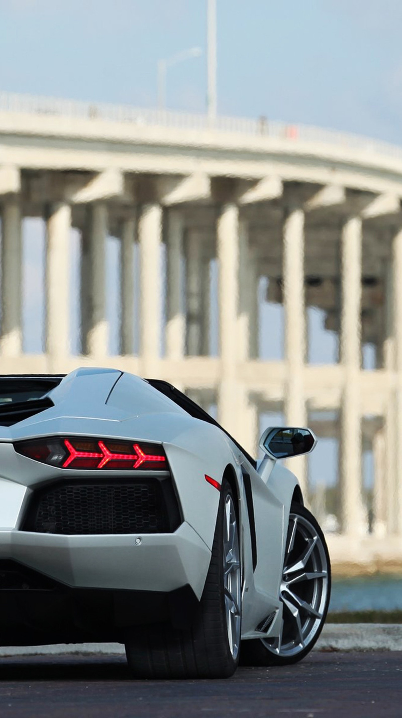 Arafed sports car parked in front of a bridge with a bridge in the background (2015, aventador, car, city, lamborghini)