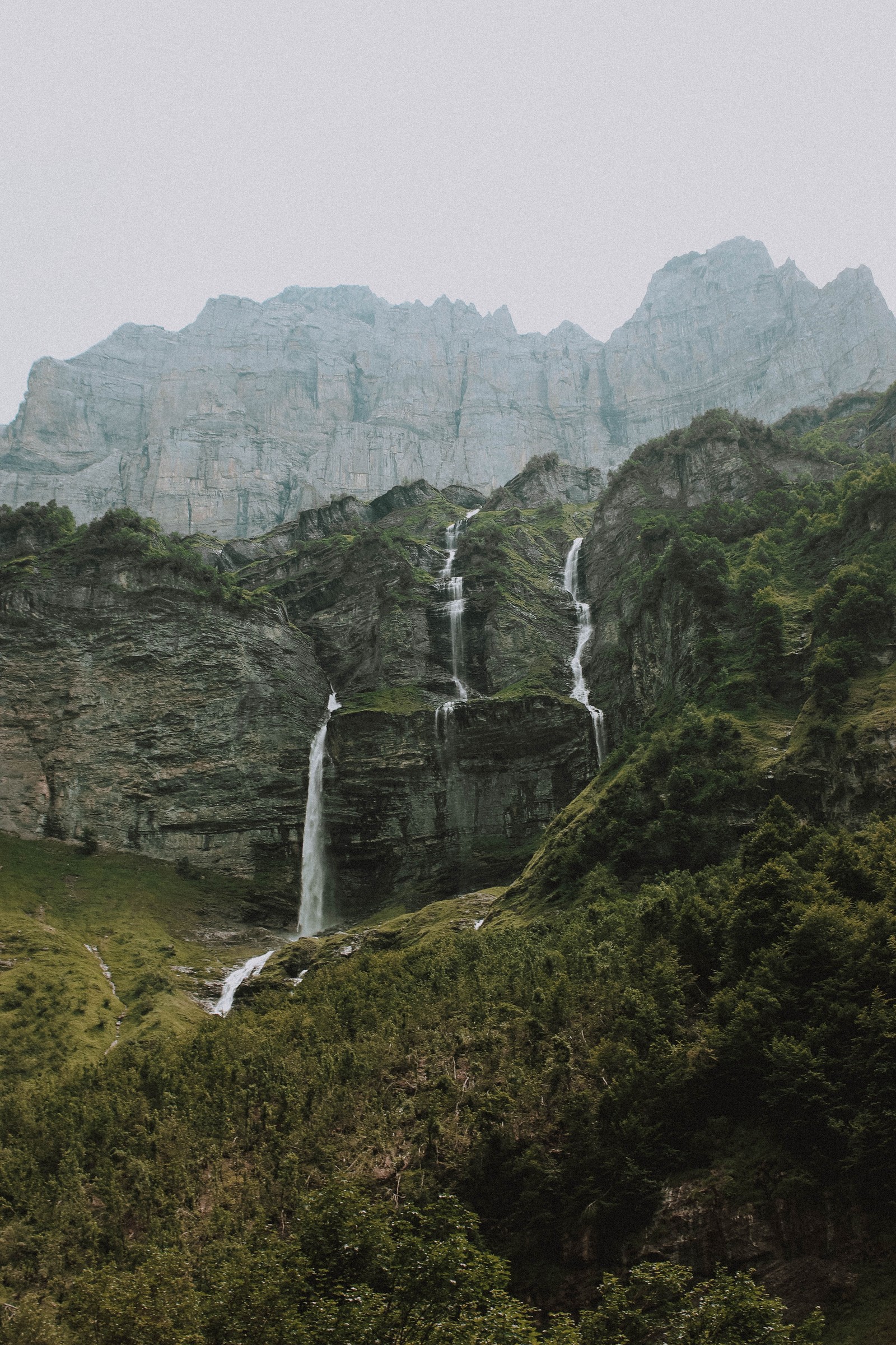 Uma cachoeira no meio de uma montanha com algumas árvores (vale, cachoeira, paisagem natural, penhasco, cenário de montanha)