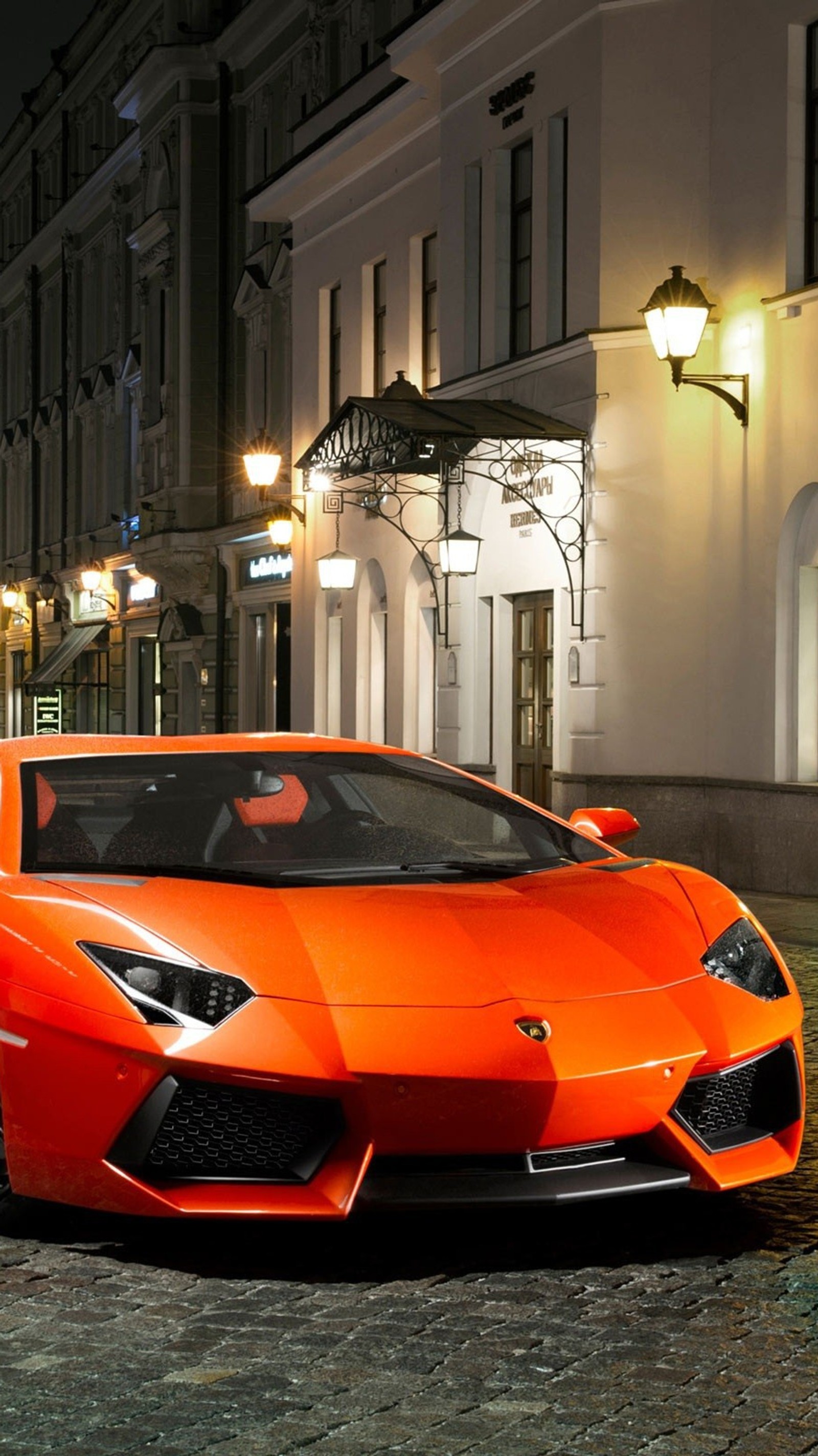 Coche deportivo árabe naranja estacionado en un adoquinado frente a un edificio (lambo)