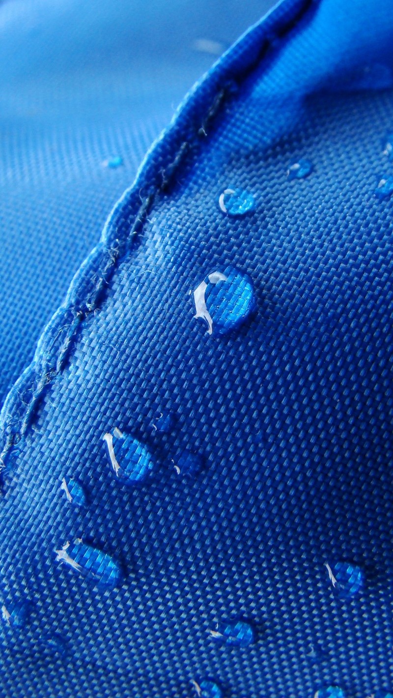 Un primer plano de una camisa azul con gotas de agua en ella (azul, tela, gotas, superficie)