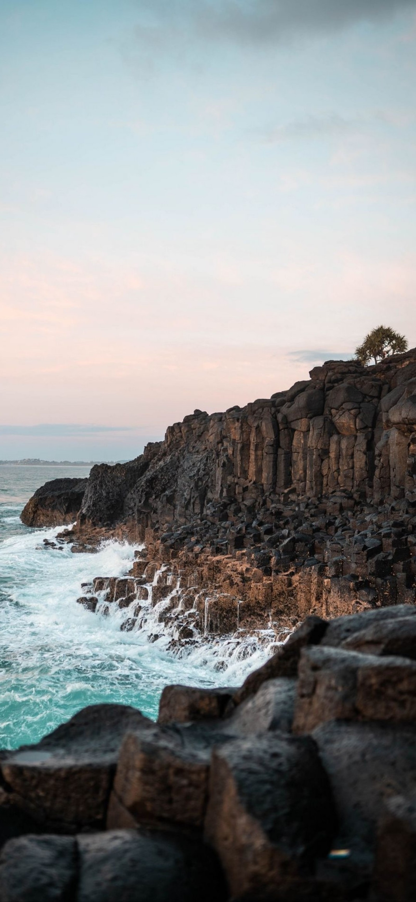 There is a man standing on a rock by the ocean (sea, coast, cloud, water, natural landscape)