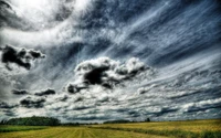 Dramatische Wolkenlandschaft über goldenen Feldern bei Sonnenuntergang