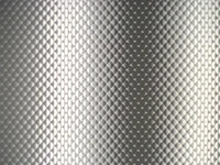 Textured metallic surface of a fluorescent lamp in monochrome, showcasing intricate patterns and light reflections.