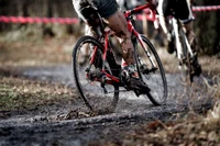 Dynamischer Radfahrer, der durch schlammiges Gelände bei einem Cross-Country-Rennen navigiert