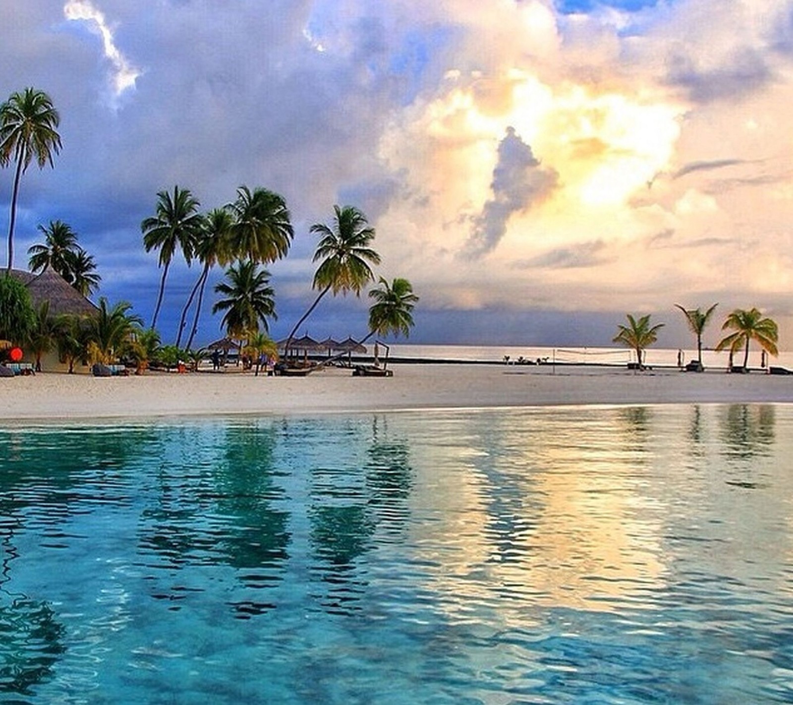 There is a view of a beach with palm trees and a boat (beach, tropical)