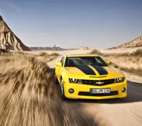 Chevrolet Camaro jaune sur une route désertique.