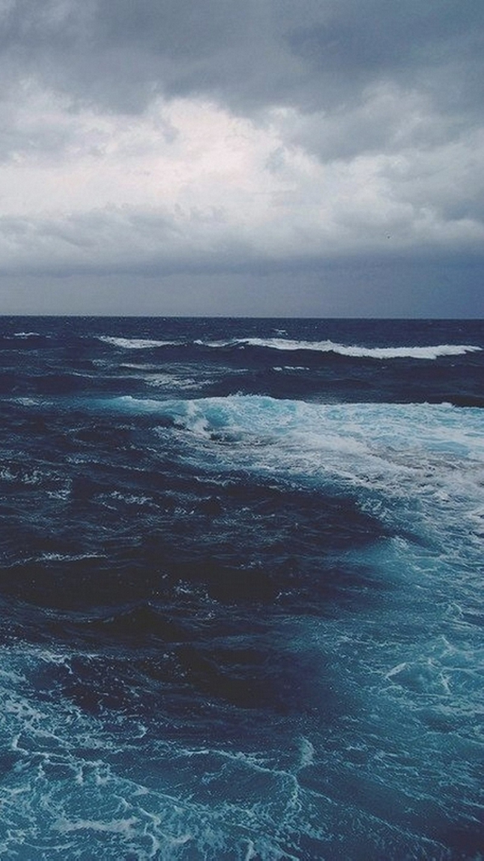 There is a large body of water with waves coming in (clouds, nature, sea, water)