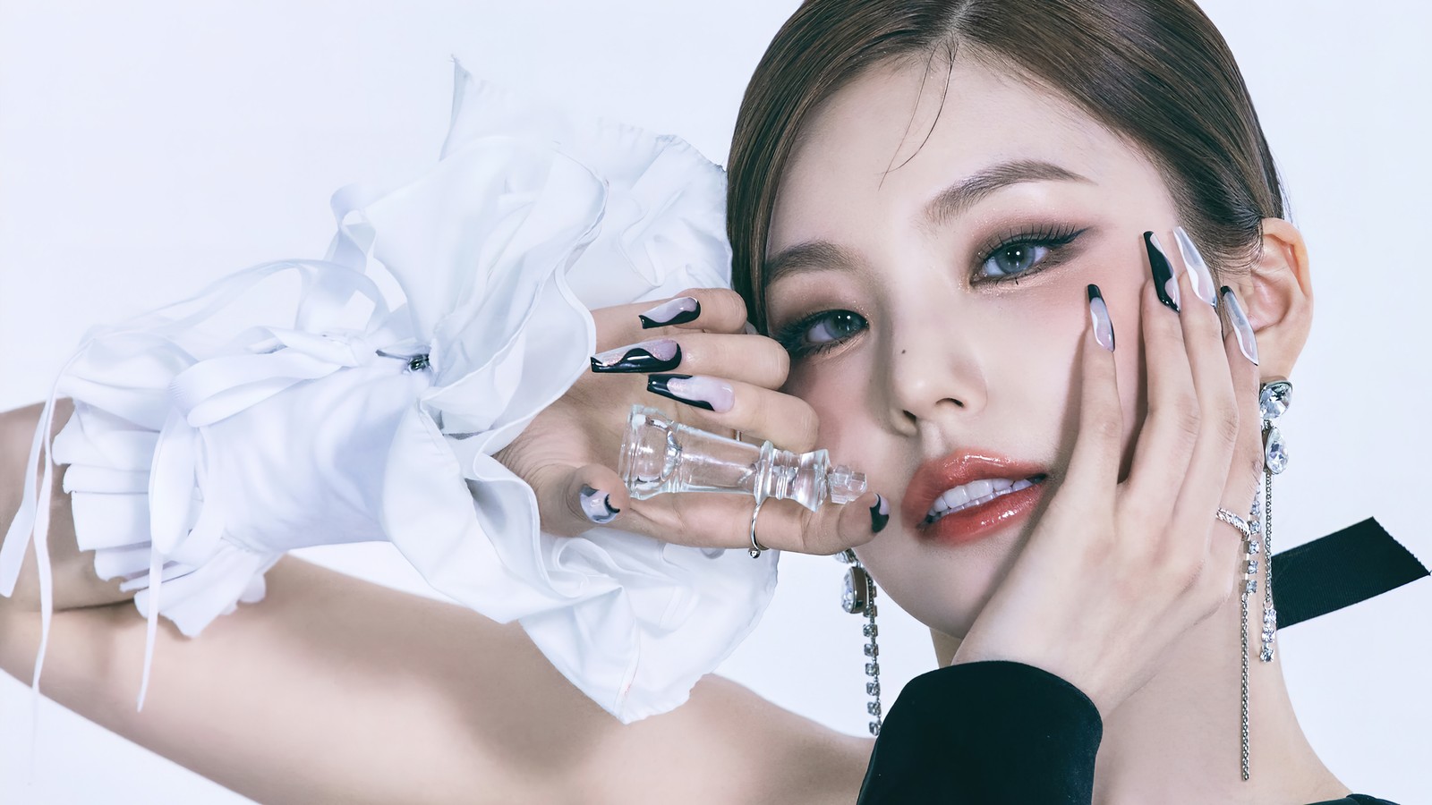 Un gros plan d'une femme en robe noir et blanc tenant une bouteille de parfum (itzy, 있지, kpop, k pop, filles)