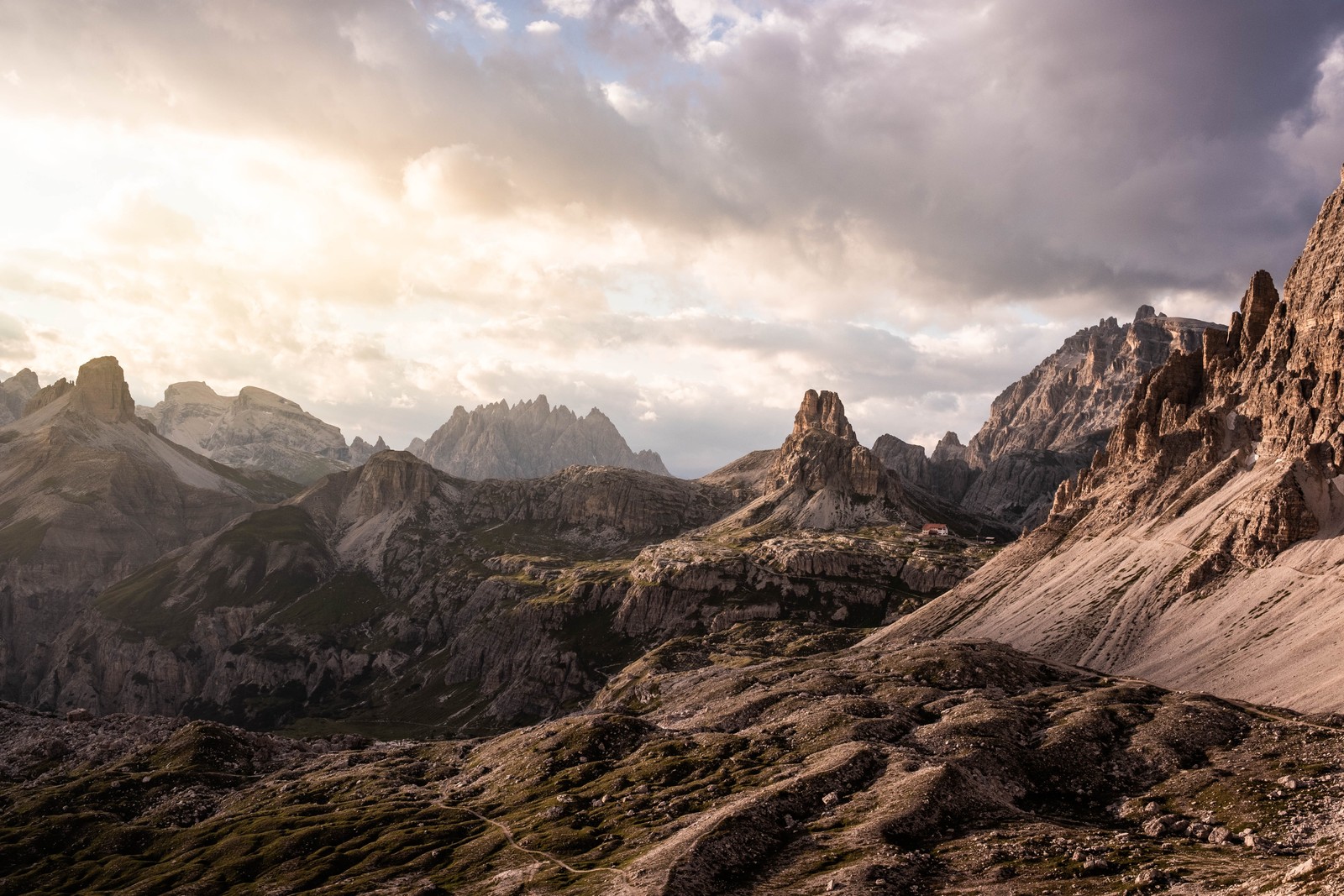 Mountains with a few clouds in the sky and a person on a bike (cloud, mountain, natural landscape, highland, bedrock)