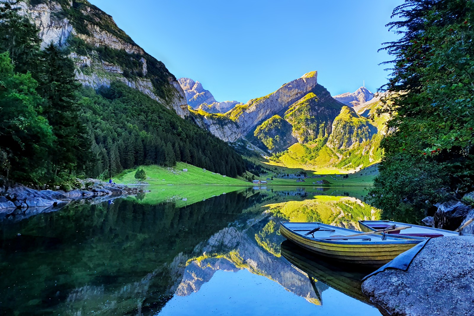 Há um barco que está na água nas montanhas (lago seealpsee, suíça, barco a remo, lago espelho, pico da montanha)