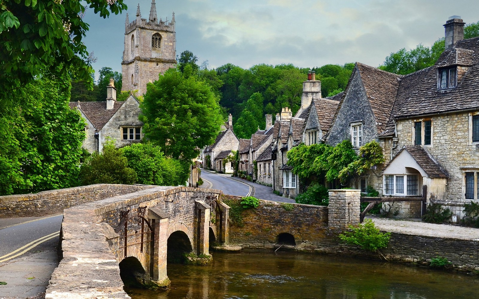 Pont en pierre courbé sur une rivière dans un village avec une tour de l'horloge (voie navigable, canal, cours deau, ville, flueve)