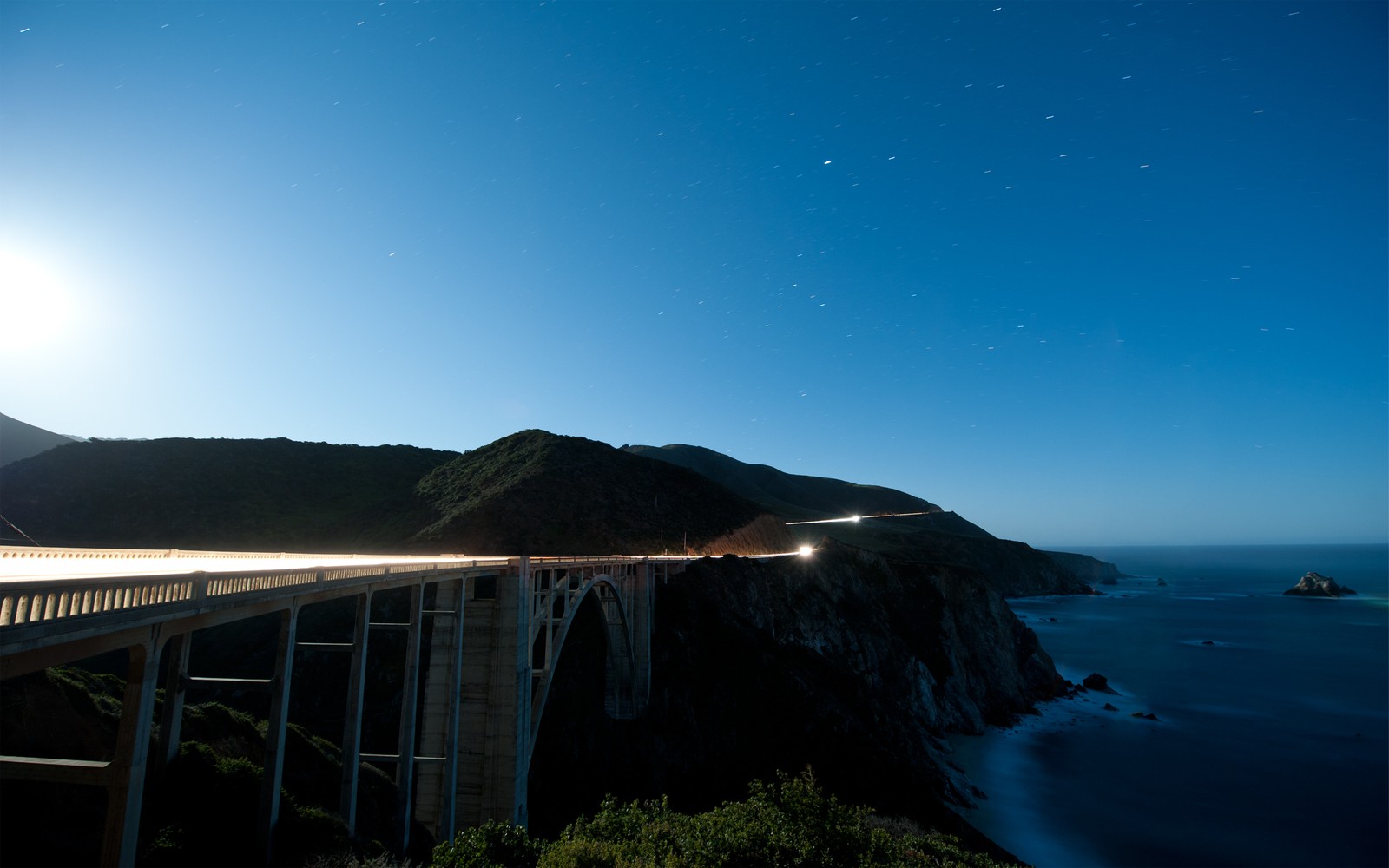 Arafed bridge over the ocean with a bright moon in the sky (sea, night, horizon, coast, headland)