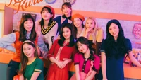 Membros do TWICE em trajes coloridos celebrando 'Kura Kura