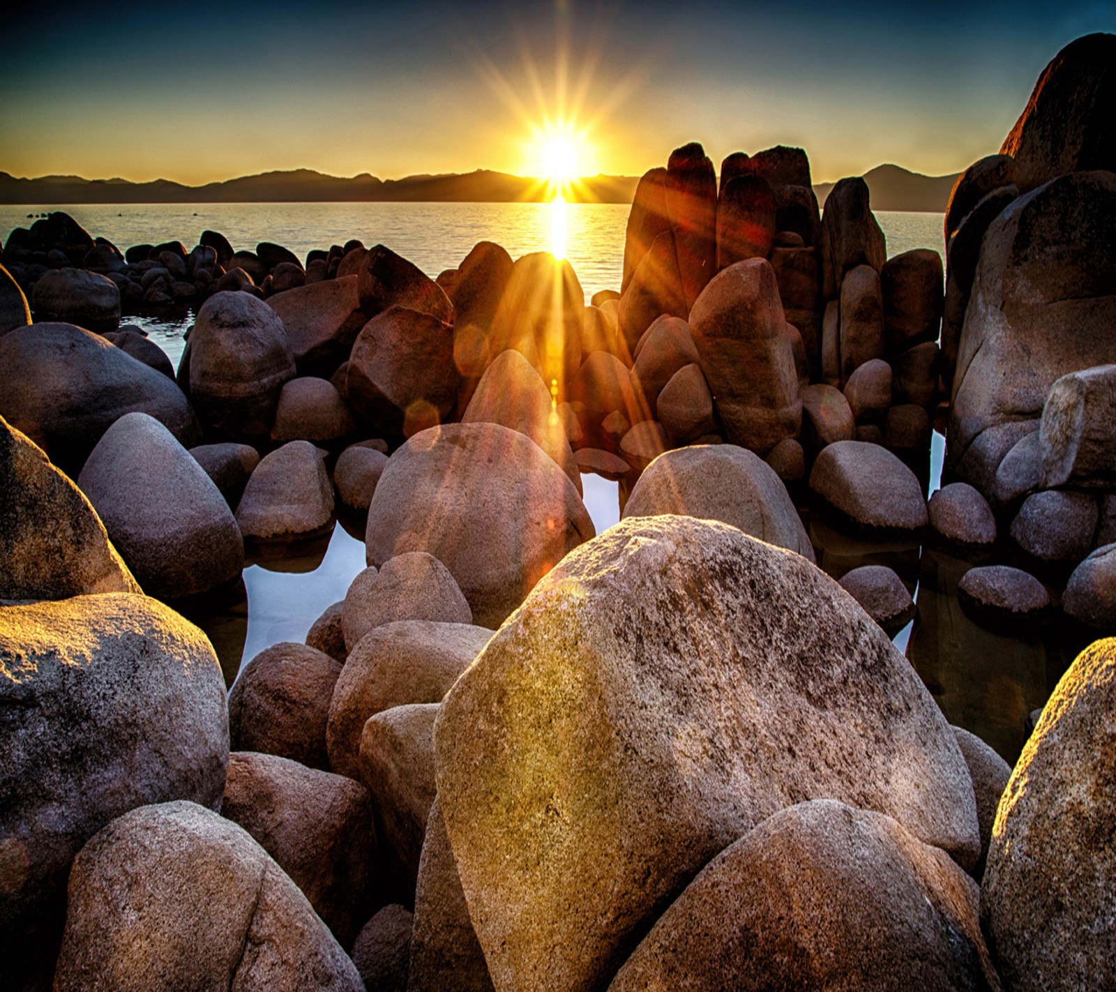 Arafed view of a rocky beach with a sun setting over the water (look, nice)