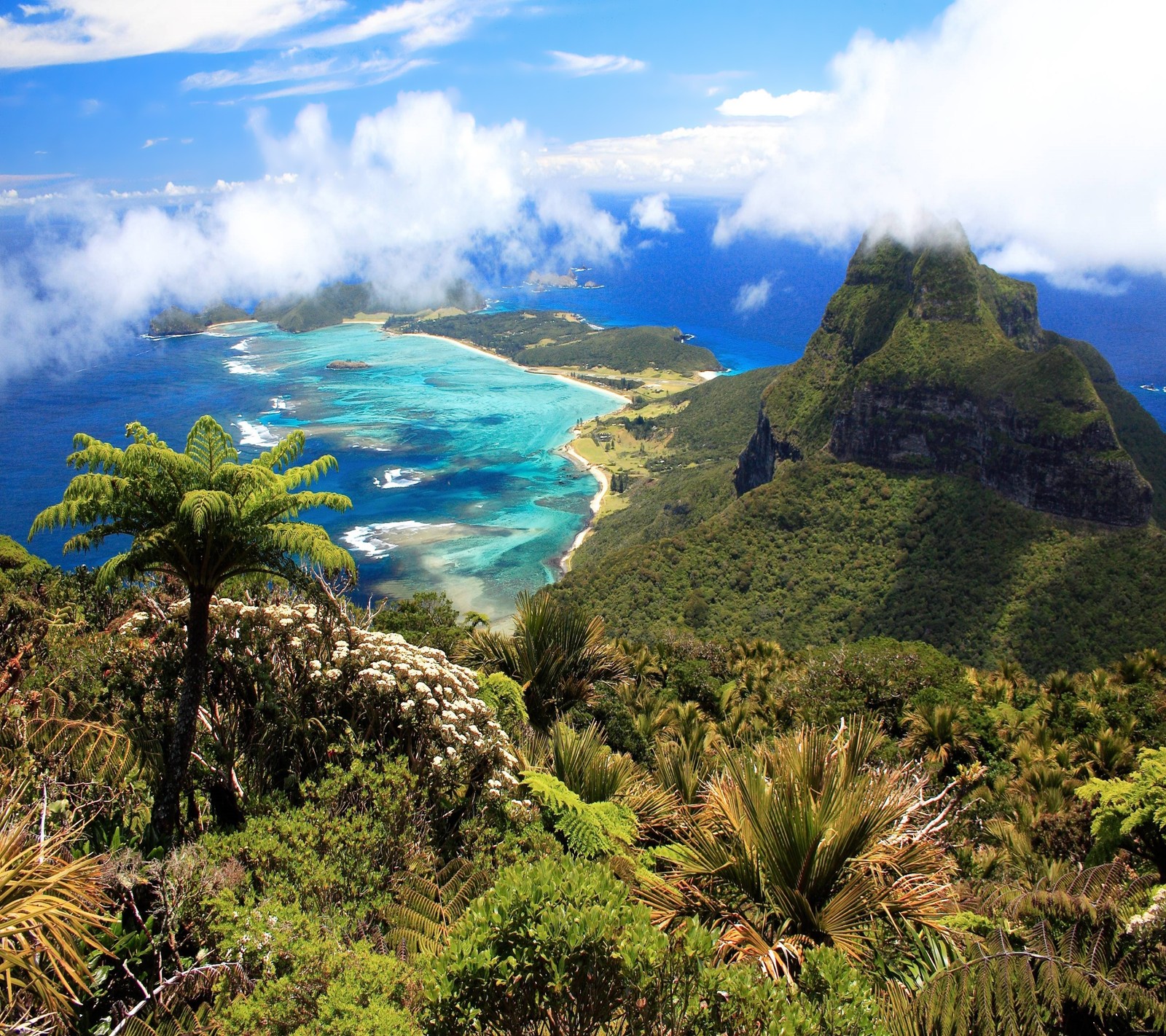 Uma vista de uma ilha tropical com uma montanha ao fundo (nuvem, ilha, montanha, oceano, paraíso)