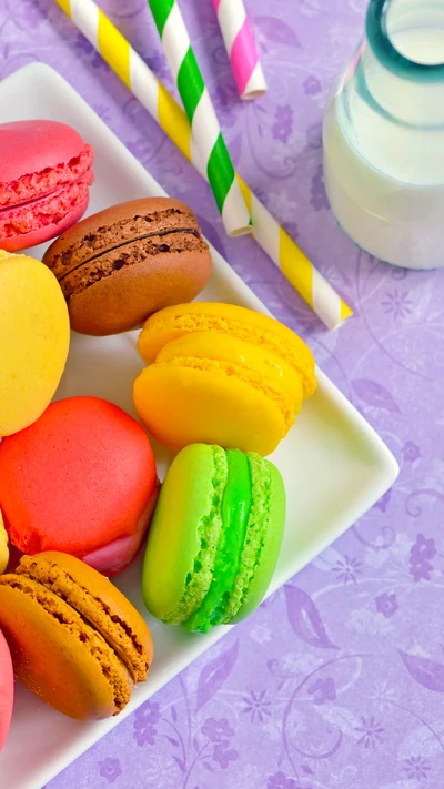 Bunte süße Macarons auf einem Teller mit Strohhalmen und Milch