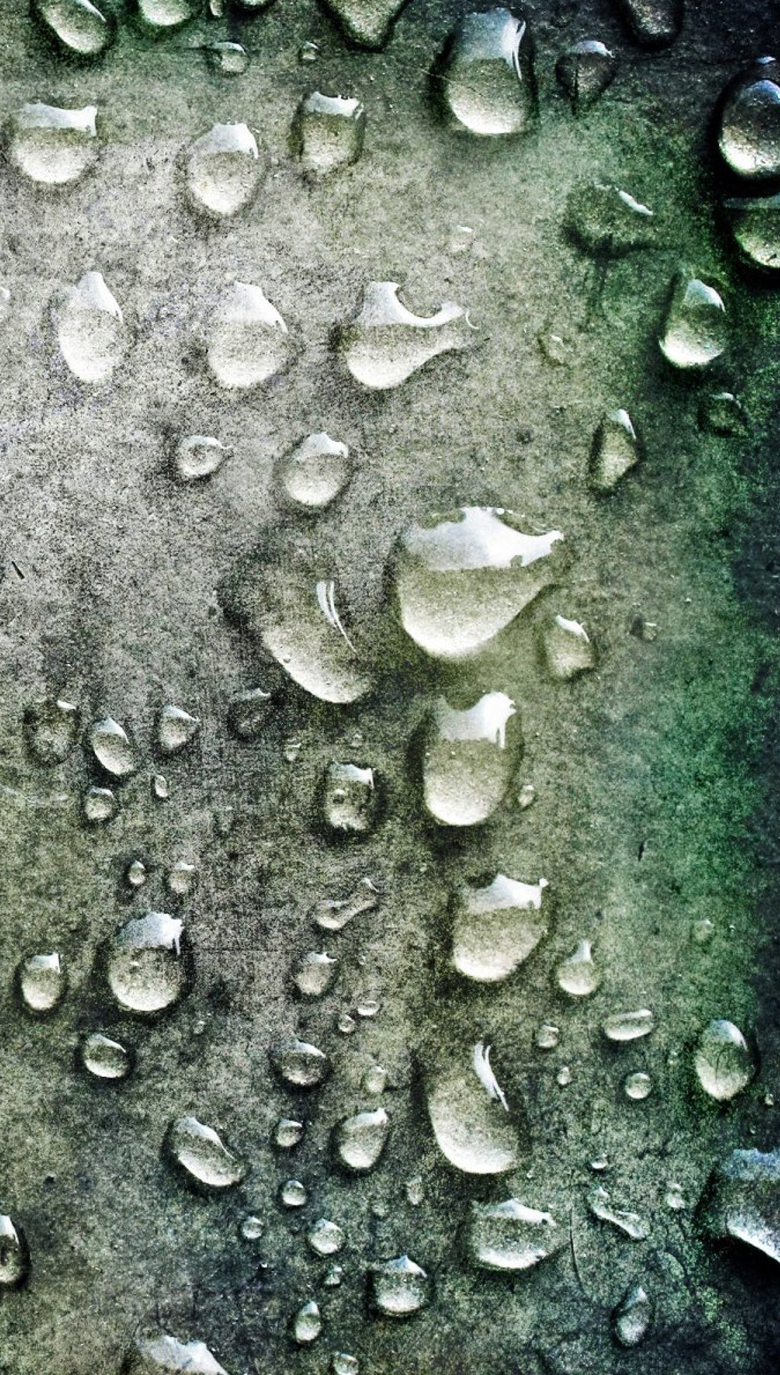 Un gros plan d'un tas de gouttes d'eau sur une surface métallique (gouttes, pluie, texture)