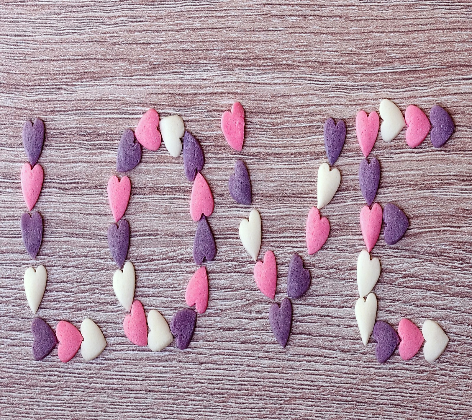 Un mot brisé fait de cœurs sur une surface en bois (bonbons, cœur, amour, doux)