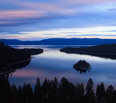 Amanecer sereno sobre un lago tranquilo con costas bordeadas de pinos