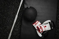 Fitness Equipment: Black Medicine Ball and White Boxing Gloves on Exercise Mat