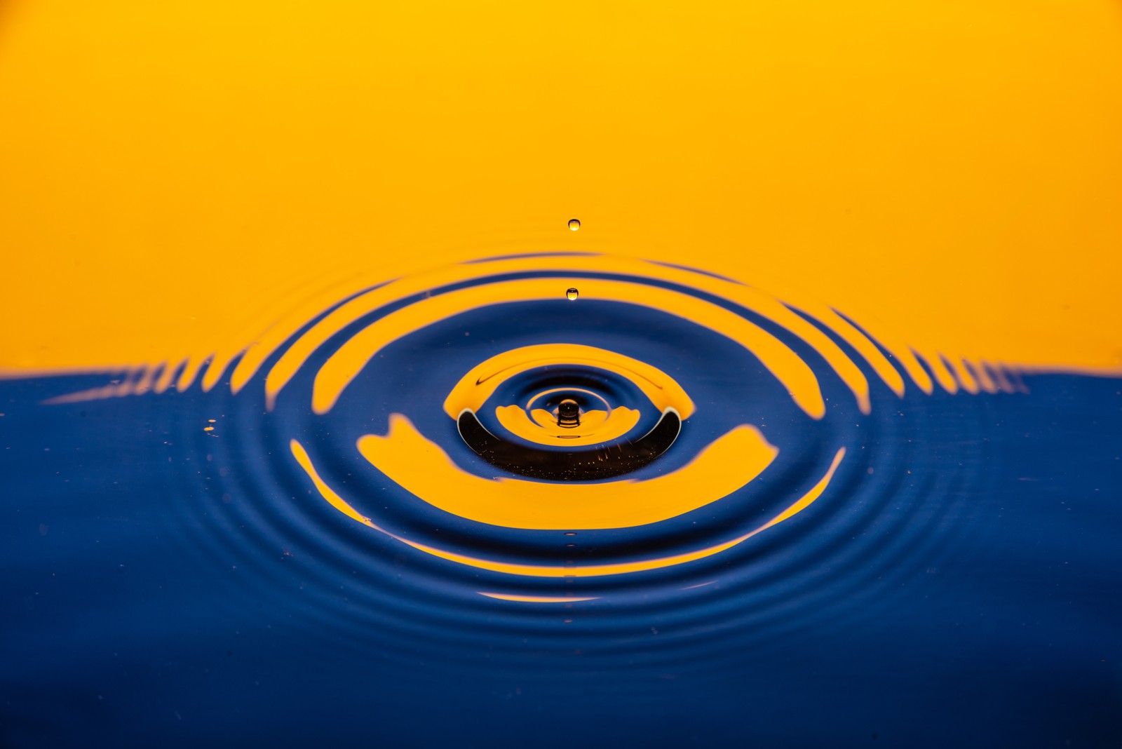 Un primer plano de una gota de agua con un fondo amarillo (gota de agua, ripple, azul, amarillo, 5k)