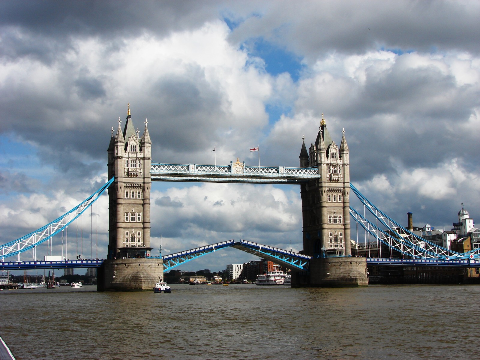 Uma ponte com corrimão azul e branco e um barco na água (tower bridge, ponte suspensa, ponte, marco, ponte golden gate)