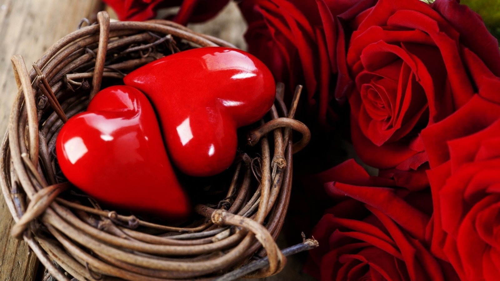 Há um coração vermelho em um ninho com rosas em uma mesa. (coração, flor, dia dos namorados, vermelho, amor)