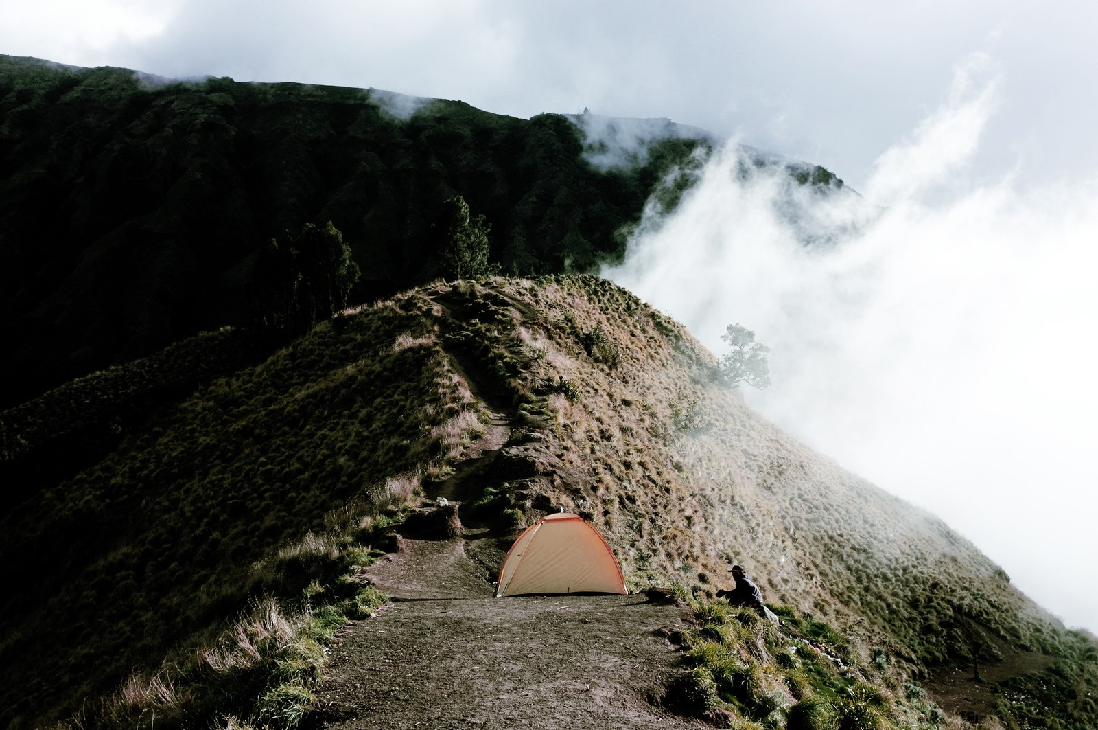 There is a tent pitched up on a mountain side (ridge, mountain, rock, hill station, sky)