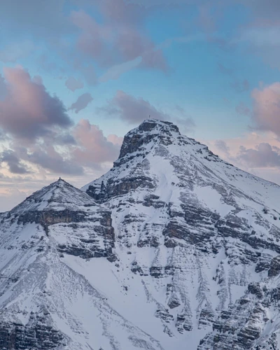 Cume coberto de neve de uma majestosa cadeia de montanhas ao crepúsculo