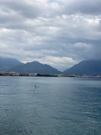 Paisaje sereno de tierras altas con montañas y aguas tranquilas bajo nubes cúmulo