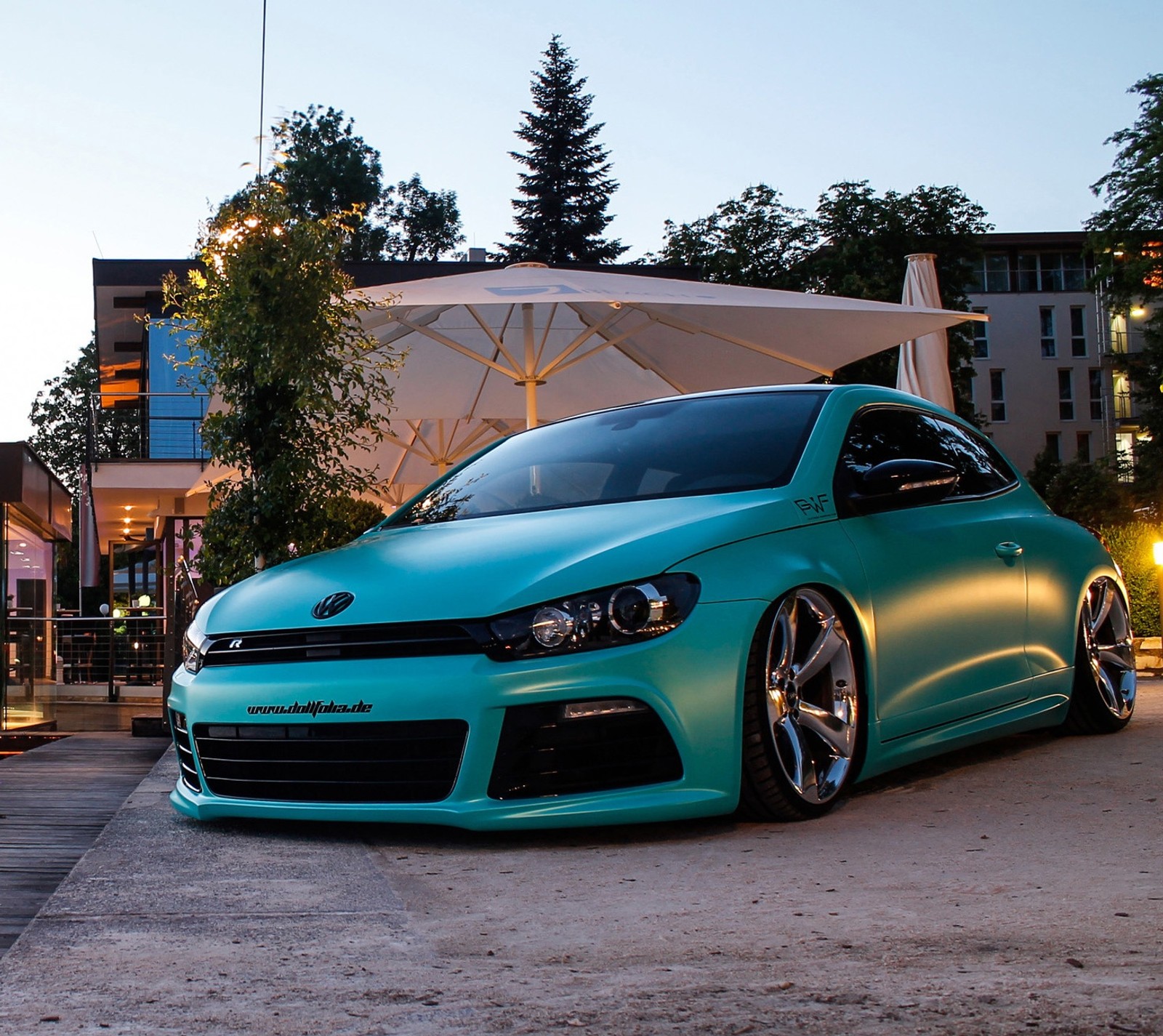 A close up of a car parked in a parking lot with a umbrella (bruxsafol, scirocco, tunning, volkswagen)