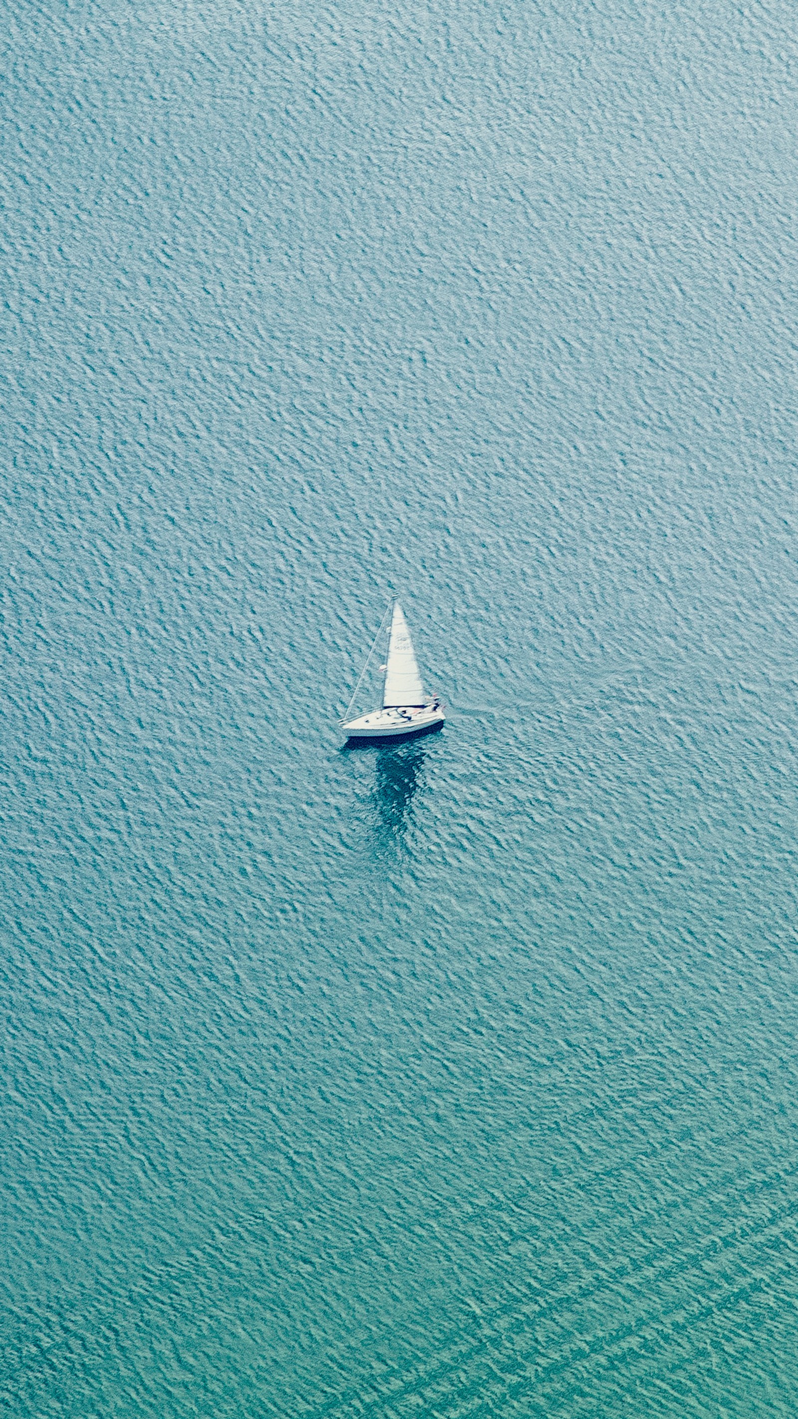 Un voilier arabe au milieu d'un grand plan d'eau (bleu, bateau, propre, minimaliste, voilier)