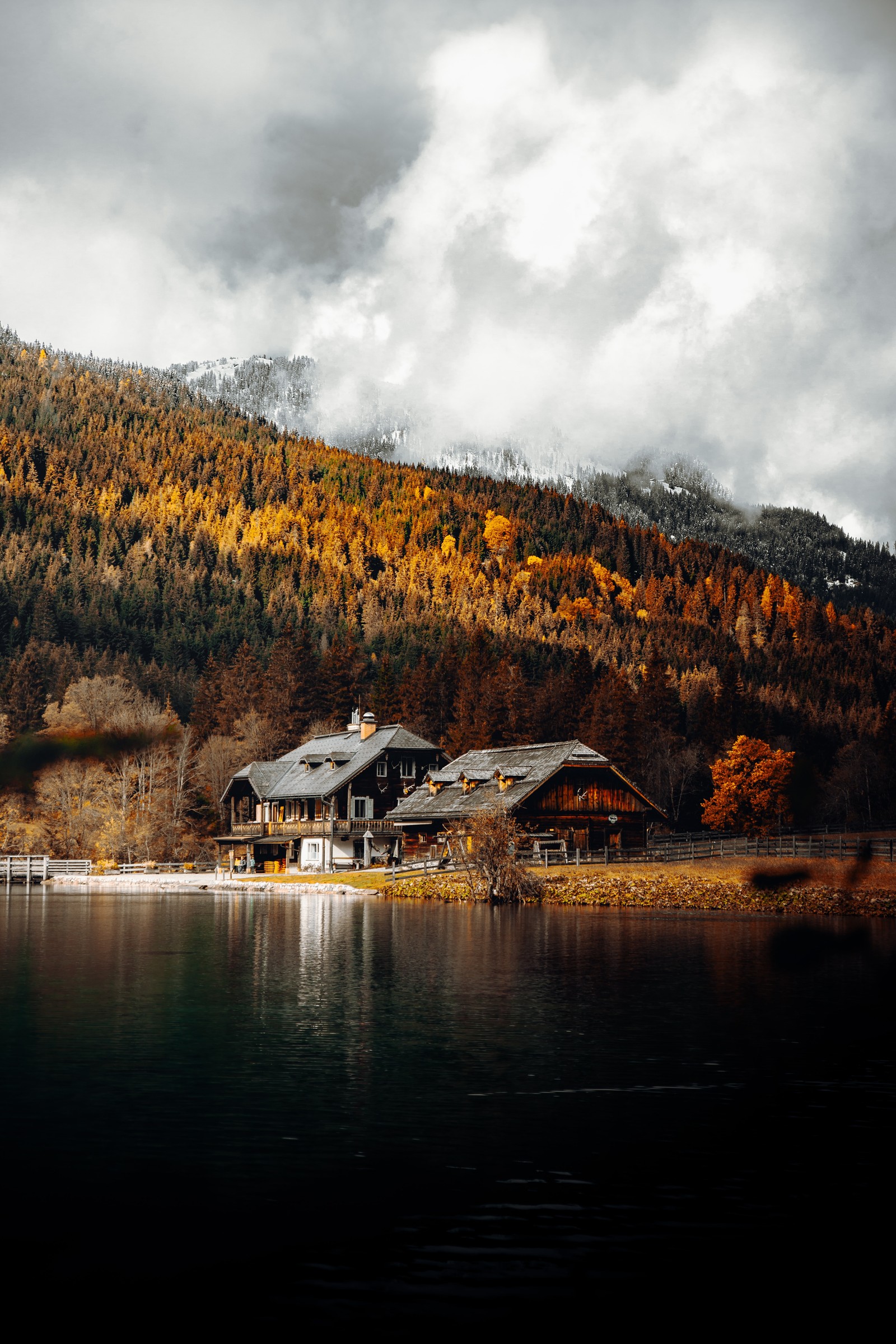 Il y a une maison sur la rive d'un lac avec une montagne en arrière-plan (maison en bois, bord de lac, arbres dautomne, campagne, montagne)