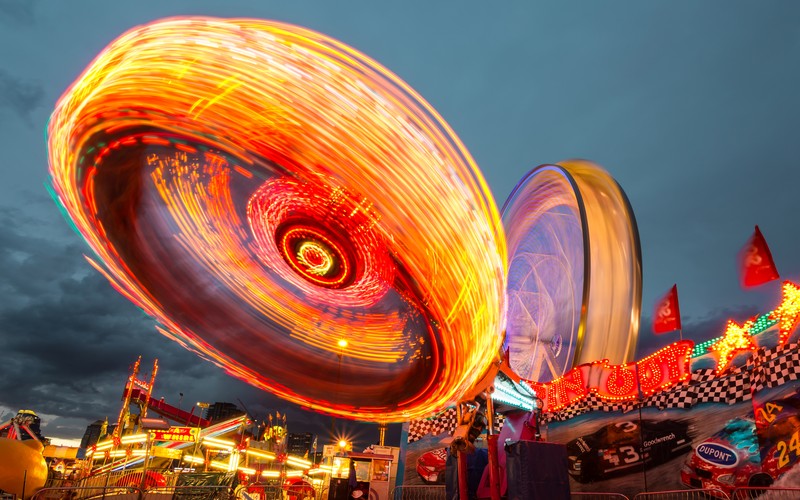 Крупный план аттракциона на карнавале ночью с размытым фоном (calgary stampede, альберта, канада, длительная выдержка, карнавала)