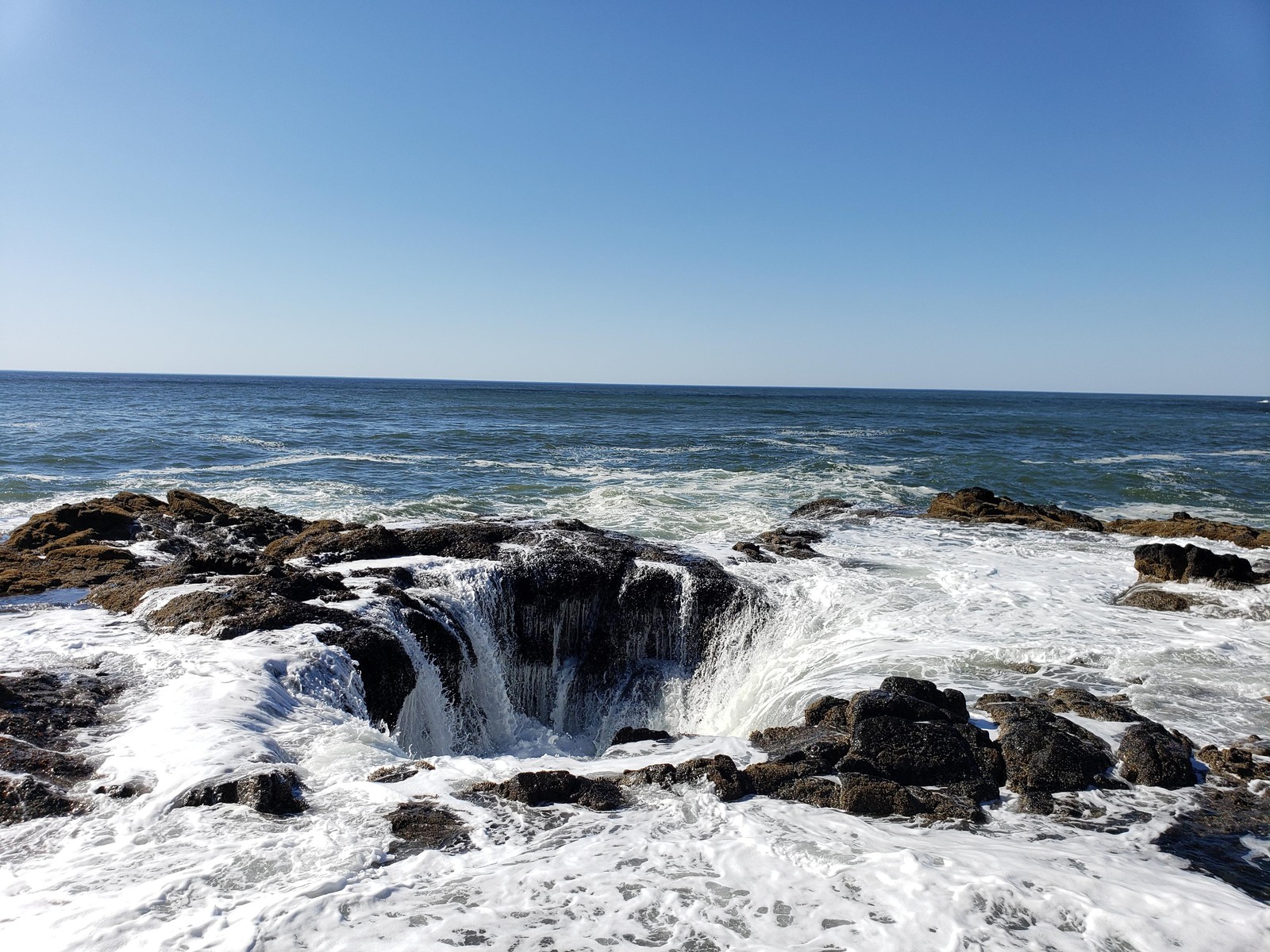 Arafed rock formation on the shore of a beach with a small waterfall coming out of it (sea, water, fluid, natural landscape, wind wave)