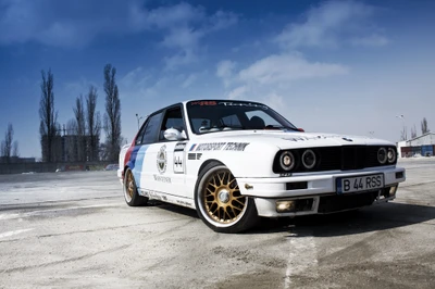 BMW E30 M3 dans une livrée de sport emblématique, mettant en valeur son héritage de course et son design sportif contre un ciel dramatique.