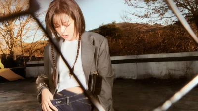 Jeongyeon from TWICE in a candid moment, showcasing a stylish outfit with a reflective, moody background.