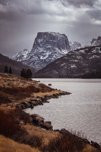 Montaña majestuosa reflejada en un lago sereno bajo cielos dramáticos