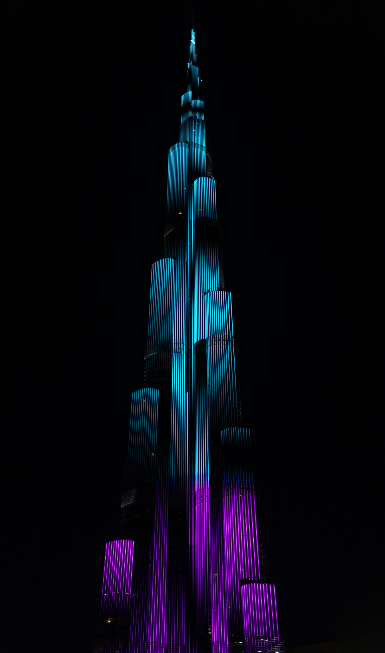 Image déformée d'un grand bâtiment illuminé en bleu et violet (burj khalifa, burj al arab, smartphone, bâtiment, gratte ciel)