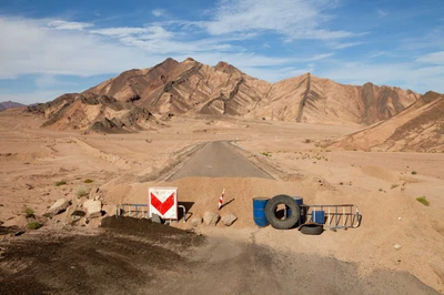 Eine raue Landschaft der Sinai-Halbinsel mit bergigen Landformen, Wüstenterrain und einer markanten Straßenbarriere, die die natürliche Schönheit der Region und ihr touristisches Potenzial zeigt.