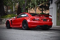 Red Mercedes-Benz SLS AMG with a sleek design and sporty rear spoiler, parked on a tree-lined street.