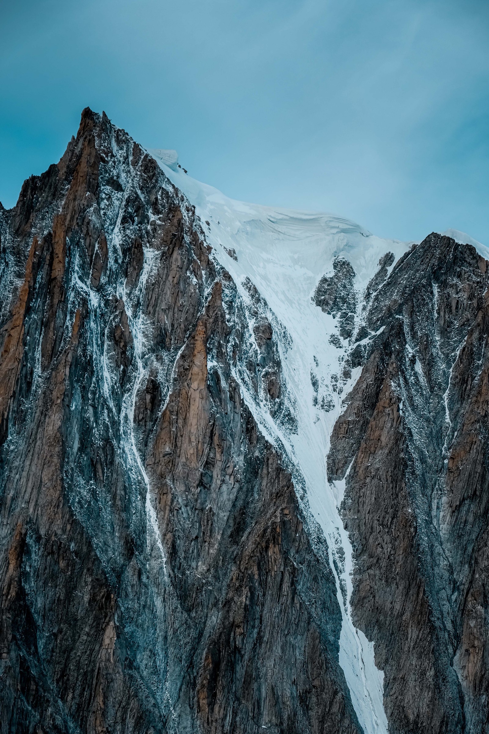 Visão arqueada de uma montanha com um pico coberto de neve e um céu azul (cadeia de montanhas, alpes, montanha, formas montanhosas, crista)