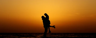 Silhouette romantique d'un couple s'embrassant au coucher du soleil sur la plage