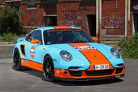 Porsche 911 Turbo com pintura Gulf, mostrando desempenho e herança de corrida.