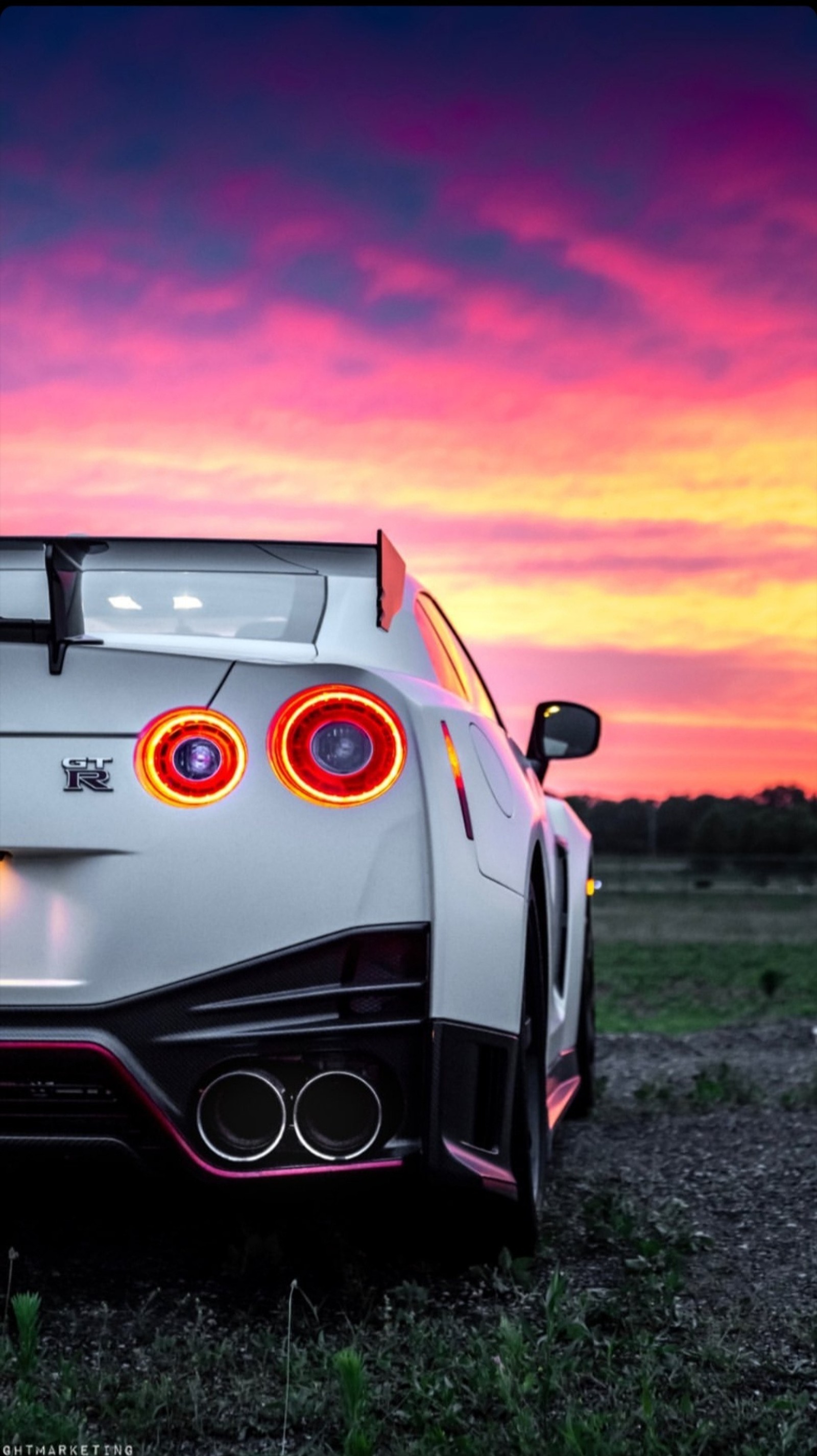 Gros plan d'une voiture de sport garée dans un champ au coucher du soleil (gtr, liberty walk, libertywalk, nismo, nissan gtr)