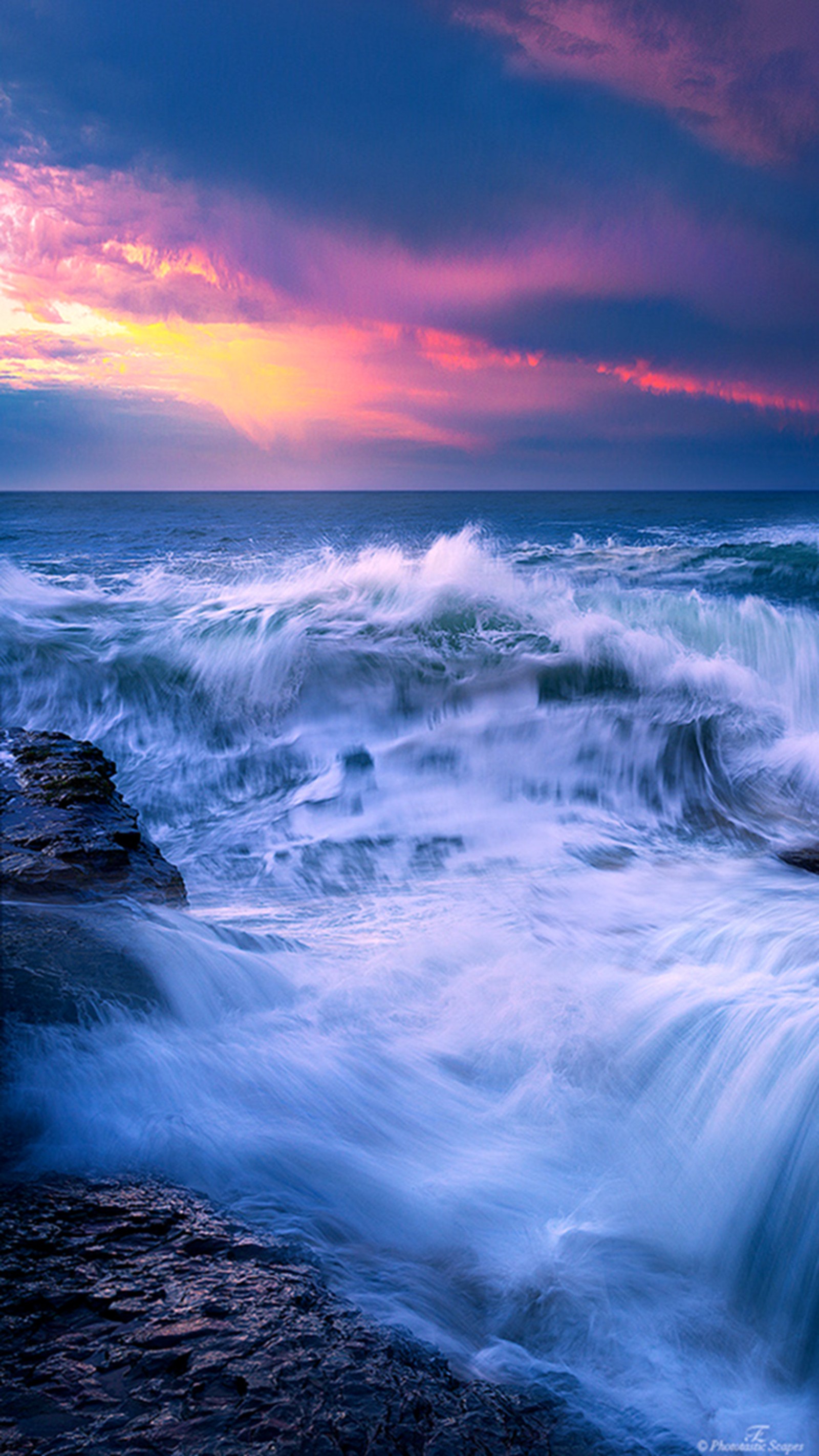 Waves crashing on the rocks at sunset with a colorful sky (beach, waves)