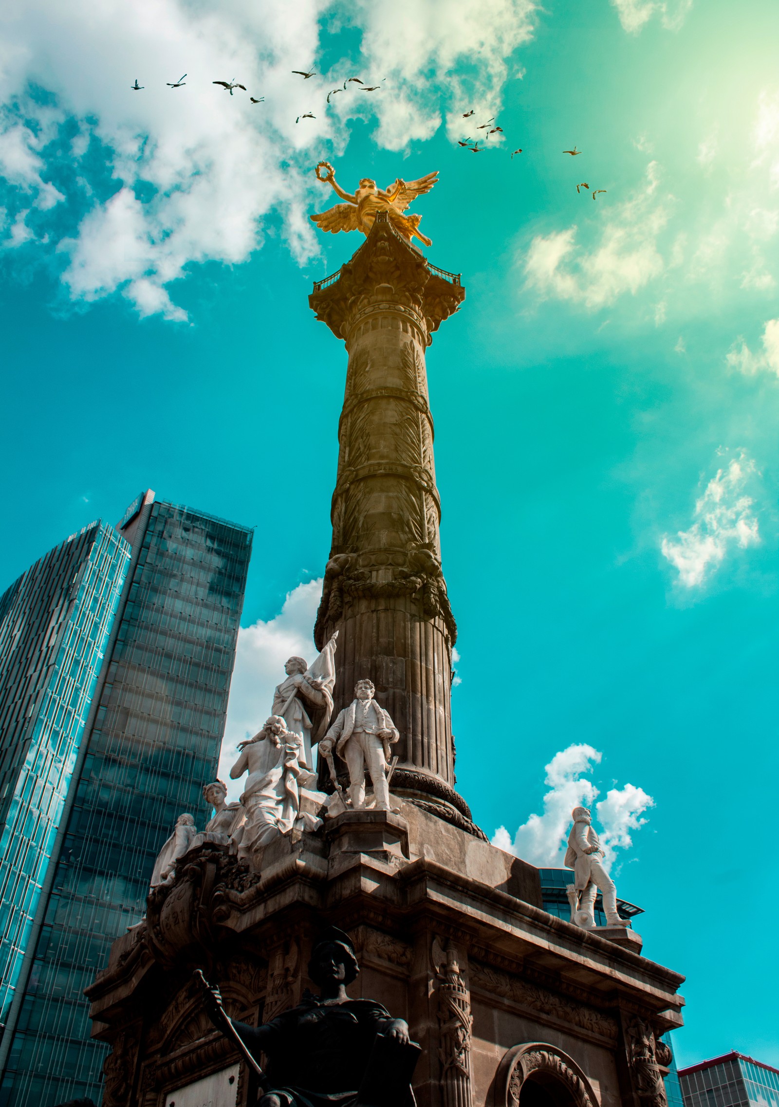 Hay una estatua en la parte superior de un edificio con pájaros volando alrededor (libertad, parís, paris, méxico, ángel)