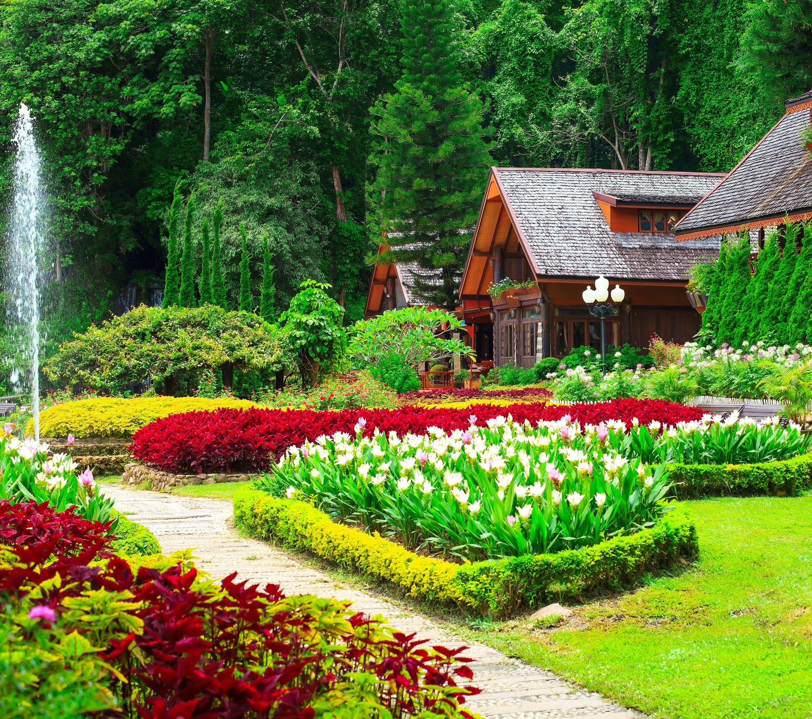 Un jardin soigné avec une fontaine et une maison en arrière-plan (jardins, vert, maison, nature, paix)